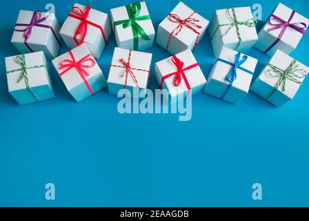 White boxes with colored ribbons lie on a blue background. Top view. Space for the text. Stock Photo