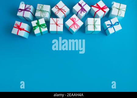 White boxes with colored ribbons lie on a blue background. Top view. Space for the text. Stock Photo