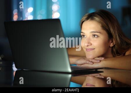 Satisfied woman watching media content on laptop in the night at home Stock Photo