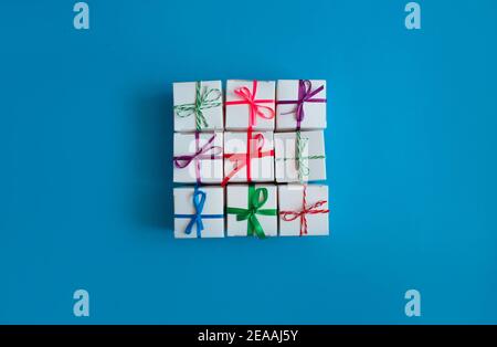 White boxes with colored ribbons lie on a blue background. Top view. Space for the text. Stock Photo
