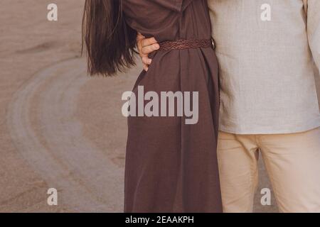 Close-up of young couple hugging outdoor. Family look linen clothes. Stock Photo