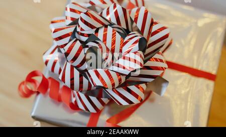 Christmas present in silver with a large red bow with an Advent star, Christmas star or poinsettie in red Stock Photo