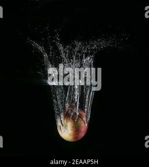 Apple that falls in the water and splashes on a black background Stock Photo