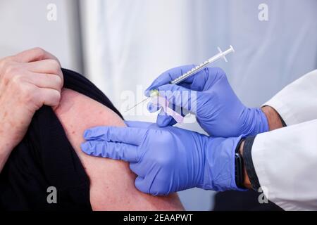 Essen, Ruhr area, North Rhine-Westphalia, Germany - Corona vaccination center Essen in the halls of Messe Essen, here more than 2, 000 people are to be vaccinated per day, in a test run a doctor vaccinates a person who is vaccinated Stock Photo