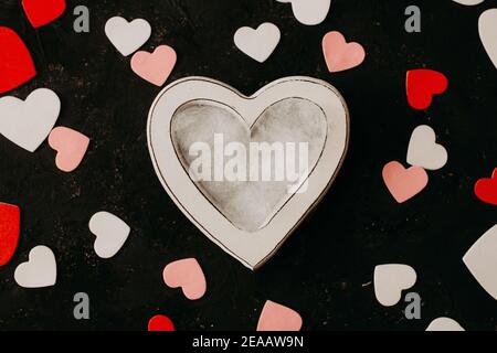 Valentines day newborn photography background - white heart shaped bowl with white, pink and red hearts on burgundy backdrop. Stock Photo