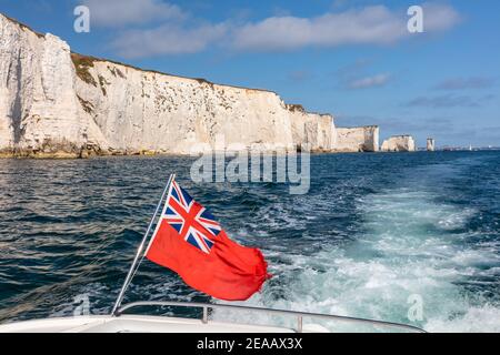 British Red Ensign flag on boat sailing past Old Harry Rocks, Dorset, England Stock Photo