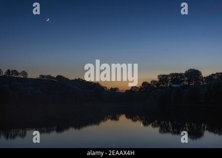 crescent moon, planet venus and mercury over lake at sunset, Weinfelder Maar, Germany, Daun, Stock Photo