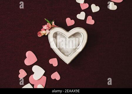 Valentines day newborn photography background - white heart shaped bowl with white, pink and red hearts on burgundy backdrop. Stock Photo