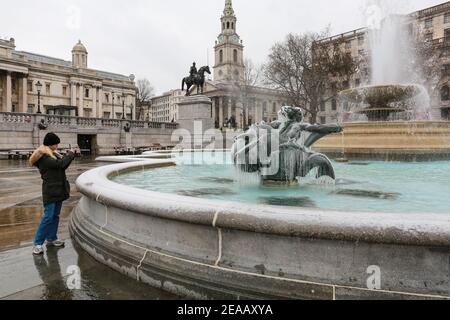 London, UK. 08 Feb 2021. UK Weather: A woman takes a photo of an ice-covered statue in a fountain in Trafalgar Square. Credit: Waldemar Sikora Stock Photo