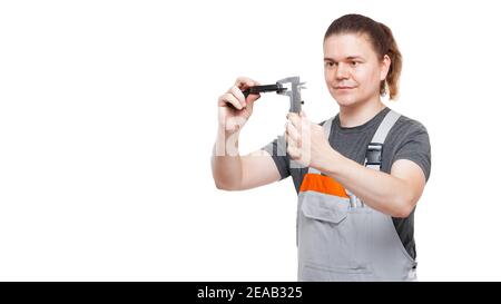 male worker in uniform of mechanic holds brake pads and calipers in hands measures asbestos size of car brakes spare part using engineer tools isolate Stock Photo
