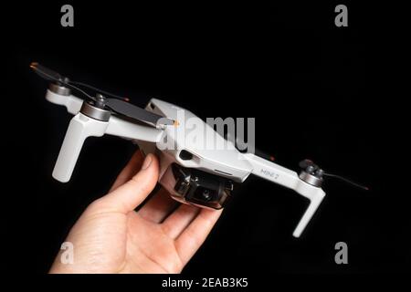 Kiev, Ukraine - February 02, 2021: Dji Mavic Mini 2 drone close-up. Hand holding unfolded quadcopter on black background Stock Photo
