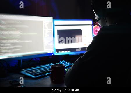 person with headphones using two computer monitors at home Stock Photo
