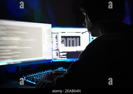 person with headphones using two computer monitors at home Stock Photo
