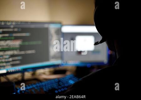 person with headphones using two computer monitors at home Stock Photo