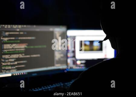person with headphones using two computer monitors at home Stock Photo