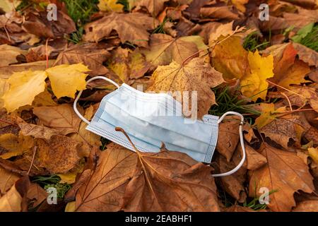 Thrown away mouth nose protective mask in the foliage, symbol photo, environmental pollution, coronavirus, on the wayside in Wilhelmshaven, Lower Saxony, Stock Photo