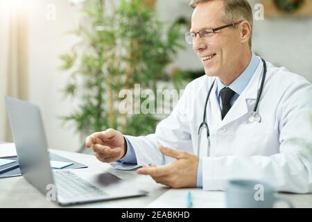 Cheerful male doctor using modern notebook in clinic Stock Photo