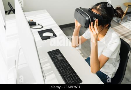 Excited young Asian woman using a virtual reality headset and joysticks, Concept connection and interfaces of digital technology. Stock Photo