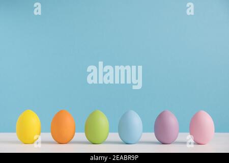 Colorful eggs on light blue background. Happy Easter background. Minimal Easter. Rainbow color Stock Photo