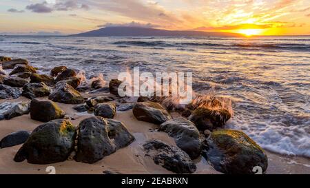 Sunset Coast - Strong waves rushing up to a rocky coast of Maui Island at the sunset. Hawaii, USA.