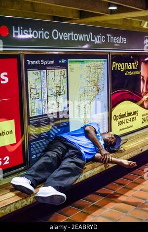 A man sleeps on a bench in the Historic Overtown Metrorail Station in downtown Miami, Florida. Stock Photo