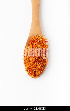 Saffron spice threads in a wooden spoon on white background. Top view. Stock Photo