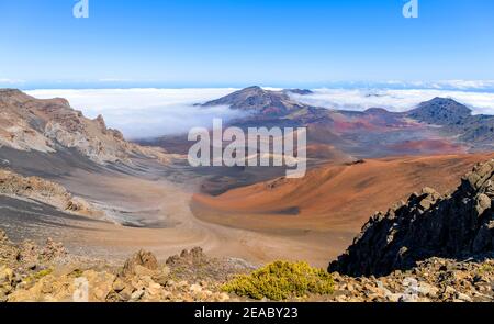 Haleakala Summit - Panorama of volcanic crater at summit of Haleakala, under bright sun and blue sky, and surrounded by sea of clouds. Maui, Hawaii. Stock Photo