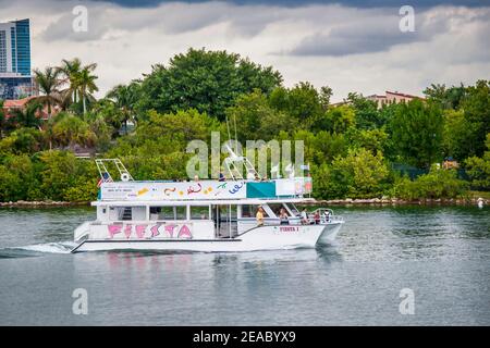 A tour boat passes by a Venetian Causeway island seen from a walkway at Jungle Island in Miami, Florida. Stock Photo