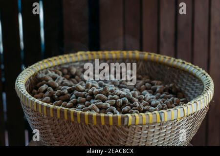 Freshly steamed peanuts sitting in a woven basket with steam rising off of them. In front of a wooden fence. Stock Photo