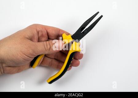 Yellow pliers in a man's hand on a white background. Stock Photo
