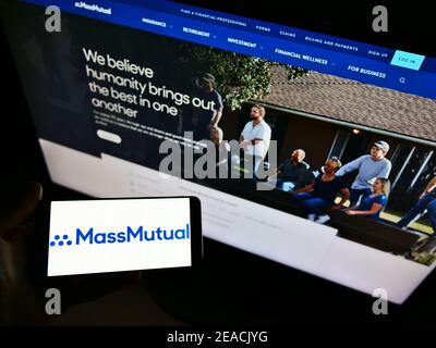Person holding smartphone with business logo of US insurance company MassMutual on screen in front of website. Focus on phone display. Stock Photo