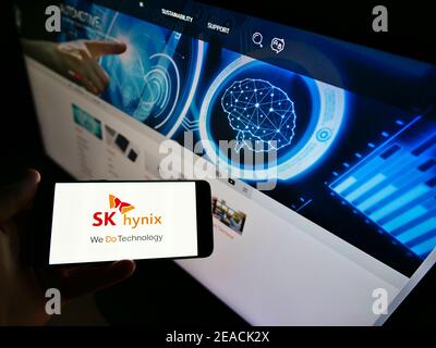 High angle view of person holding mobile phone with logo of South Korean semiconductor supplier SK hynix Inc. on screen. Focus on cellphone display. Stock Photo