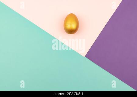 Abstract geometric paper background of pastel pink and purple colors with golden easter egg. Copy space for design. Stock Photo
