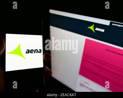 Person holding smartphone with logo of Spanish airport operator Aena S.A. on screen in front of business website. Focus on phone display. Stock Photo