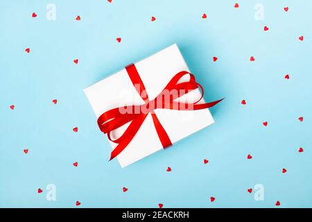 Trendy attractive minimalistic gift on the blue background with hearts. Merry Christmas, St. Valentine's Day, Happy Birthday and other holidays concept. Stock Photo