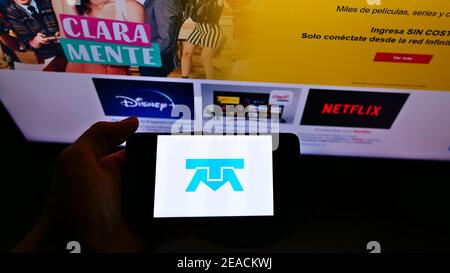 Person holding smartphone with logo of Mexican telecommunications company Telmex on screen in front of business website. Focus on phone display. Stock Photo