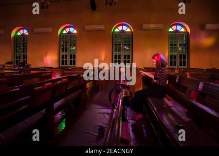Woman sitting and praying while reading from the Bible in Church. Religion Concept Stock Photo
