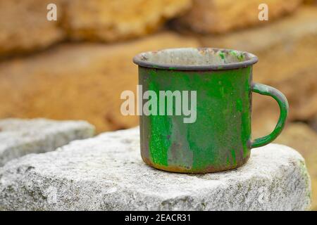 An old green enamelled mug. View from the front. Copy space. Stock Photo