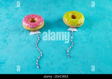 Multicolored donuts with glaze and sprinkles in the form of balloons flying in the sky. Stock Photo