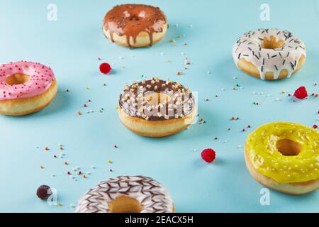 Multicolored donuts with frosting and sprinkles on blue background. Stock Photo