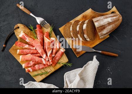 Overhead view of rolled slices of jamon on wooden cutting board Stock Photo