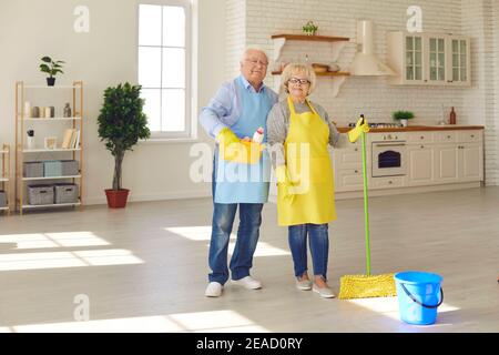 Stylish senior smiling couple standing and holding equipment for home cleaning Stock Photo