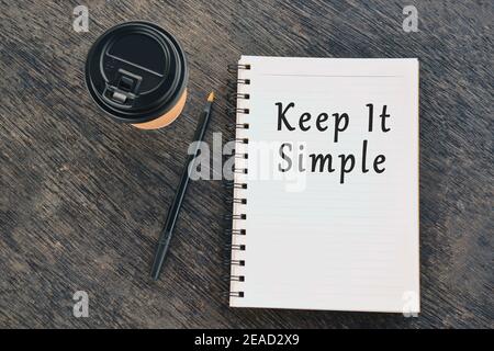 Text on notepad with disposable coffee cup and pen on wooden table Stock Photo