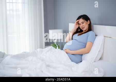 stressed pregnant woman has a headache on a bed Stock Photo