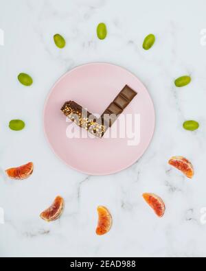 Representation of a clock made with chocolate and pieces of fresh fruit Stock Photo