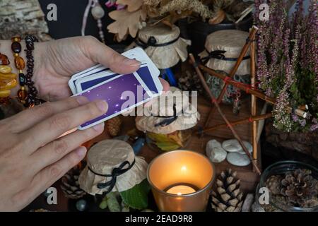 Woman hand is holding deck of tarot or oracle cards doing fortunetelling. Stock Photo