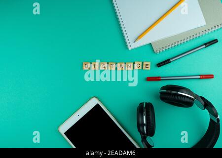 Distance. The phrase is laid out in wooden letters. View from above. Motivation. Copy space. Tablet, Headphones stationery. distance learning. Table F Stock Photo