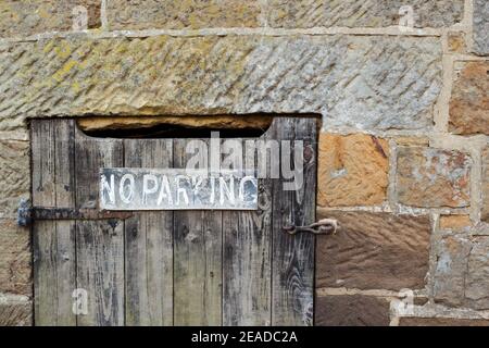 Close up view of a dressed sandstone building with a door fitted which has a No Parking sign on it Stock Photo