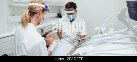 Woman having her dental treatment in clinic during pandemic. Dentists working on patient's teeth in dentistry. Stock Photo