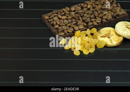 Dark or bitter chocolate with whole nuts, raisins and figs. Natural coffee beans as ingredients for Stock Photo